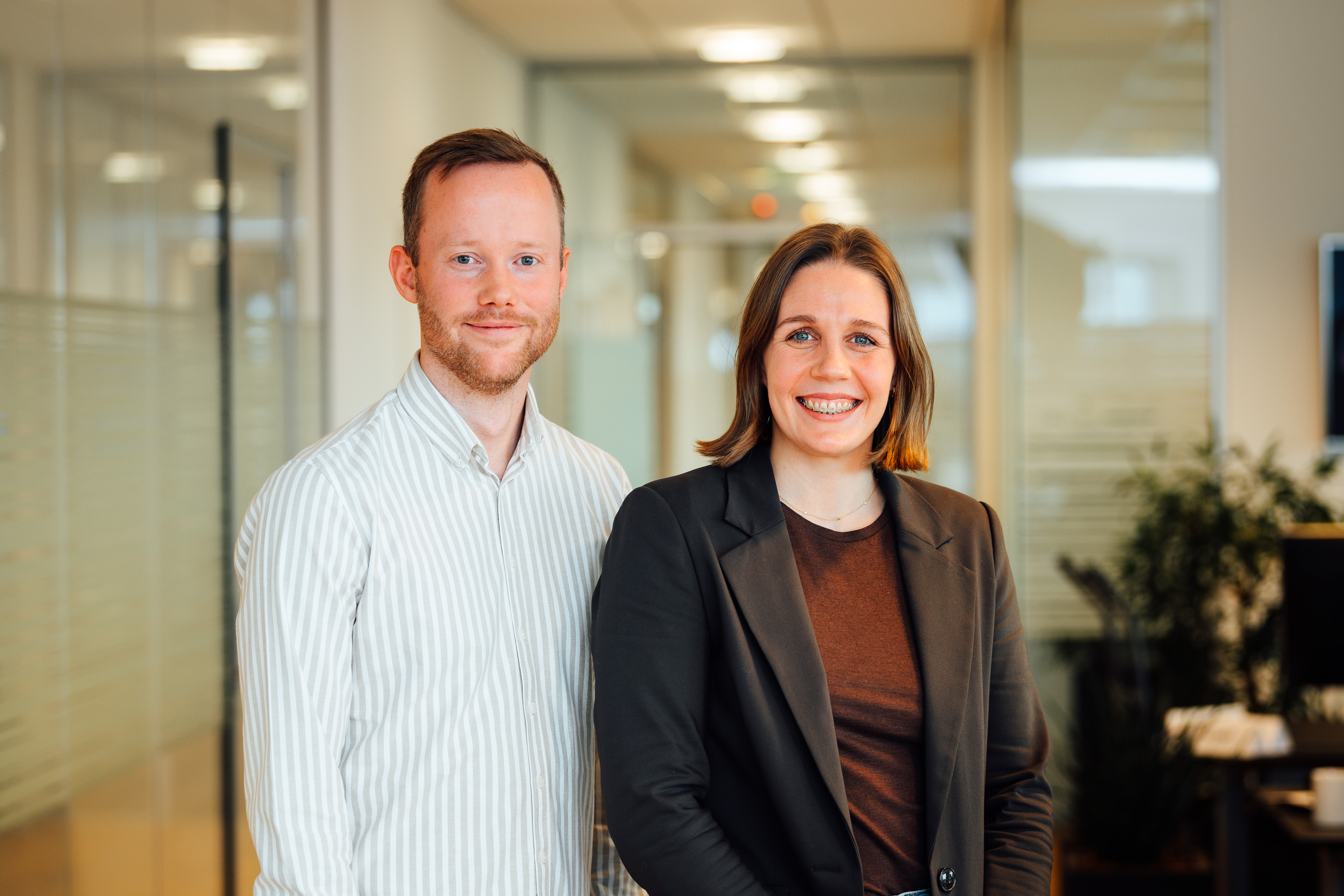 Man wearing glasses working at a desktop computer in a bright office environment