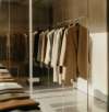 Racks of neatly arranged suits in various shades, displayed in a minimalist and well-lit showroom